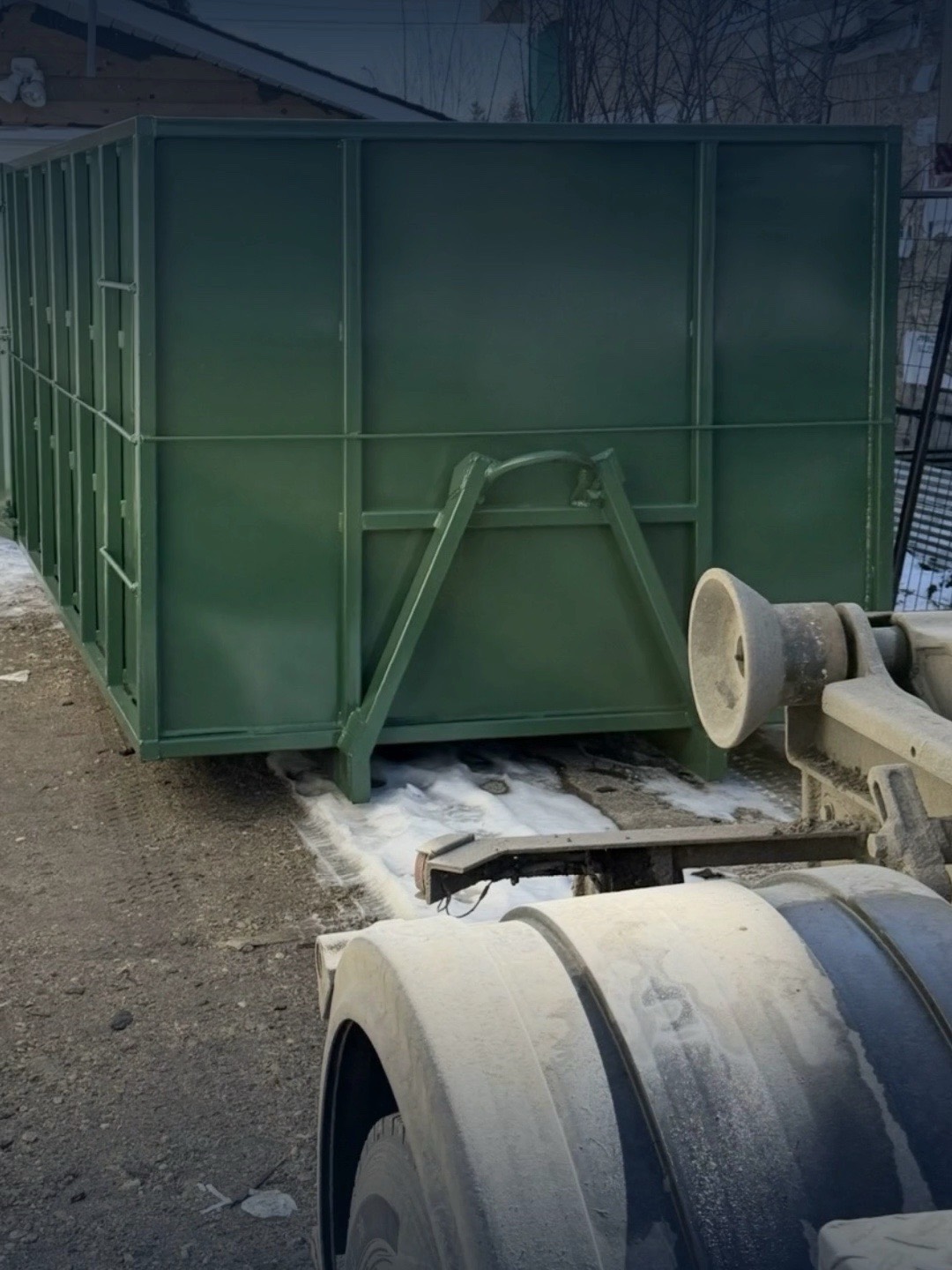 Green roll-off bin loaded on the back of a Hauling Heroes truck
