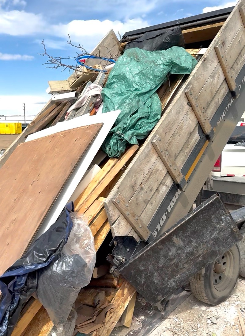 Dump trailer tipping a full load of lumber, plywood and bagged junk