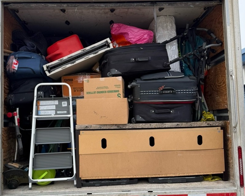 Moving truck loaded floor to ceiling with suitcases, boxes and household items